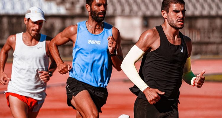 Three male athletes intensely focused on a track, captured mid-race showcasing their dedication.
