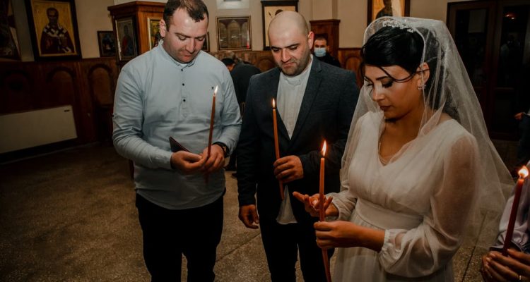 Bride and guests holding candles during an Orthodox wedding ceremony in a church setting.