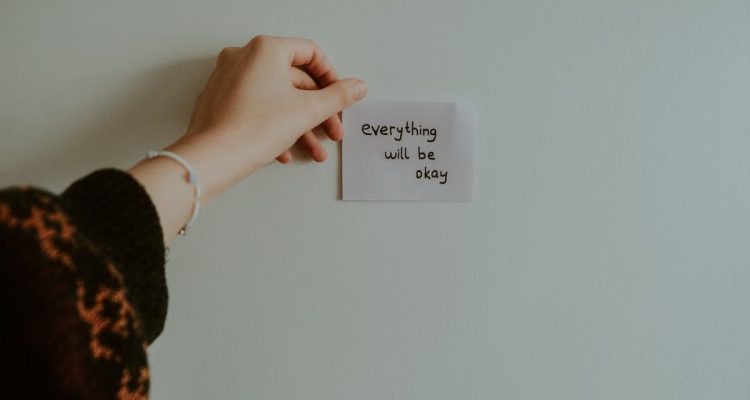 A hand holding a motivational note with uplifting text in an indoor setting.